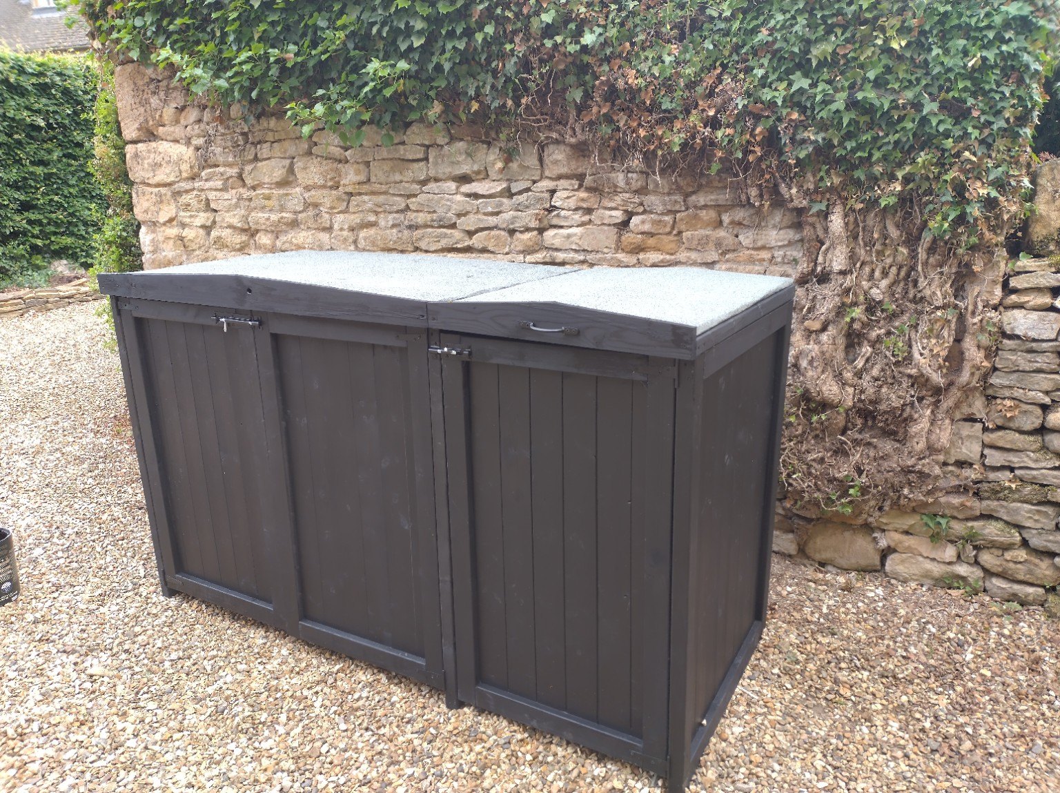 Three-bin storage beside a stone wall