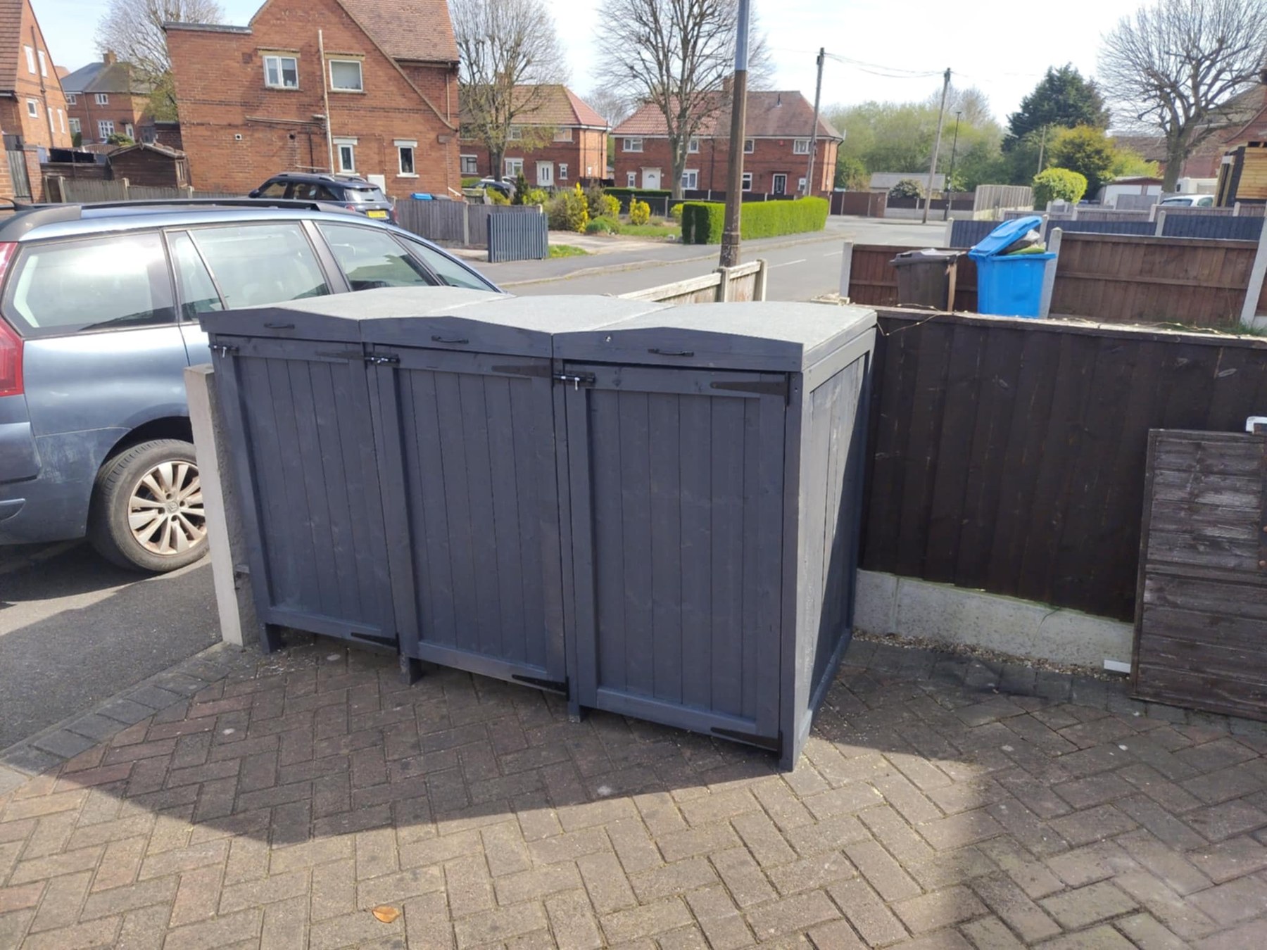 Handmade charcoal wooden wheelie bin store with three front doors and individual lifting lids